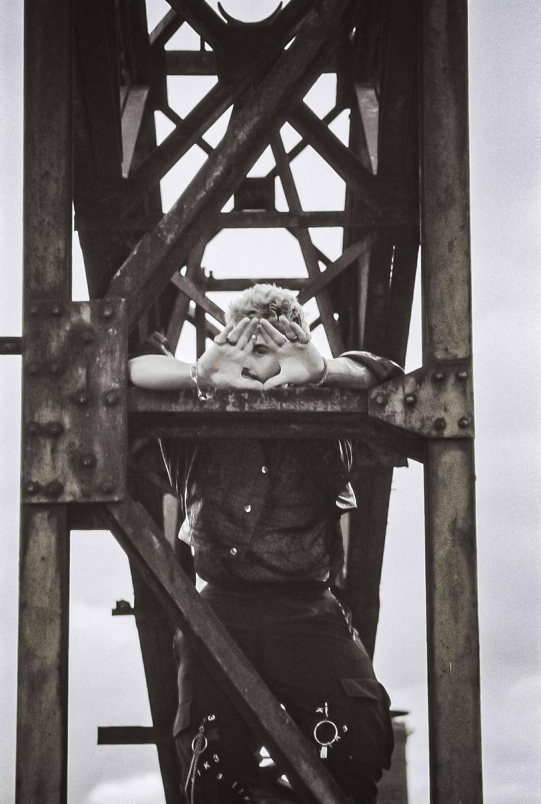 Model standing on an iron tower, creating a triangle shape with his hands. Location: Duisburg. Photo by NinoTurbaProductions