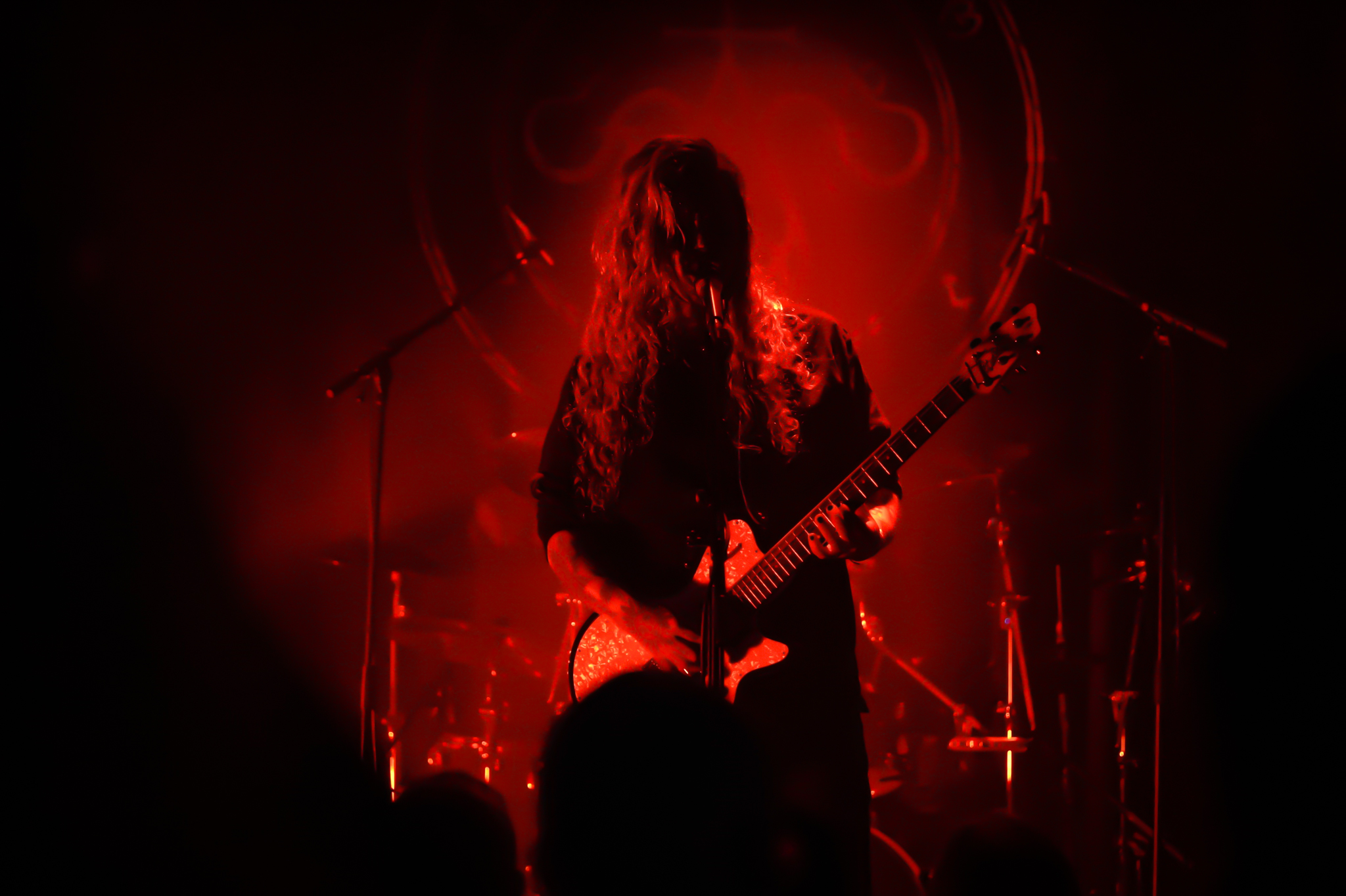 A black metal musician standing menacingly on a dimly lit stage.