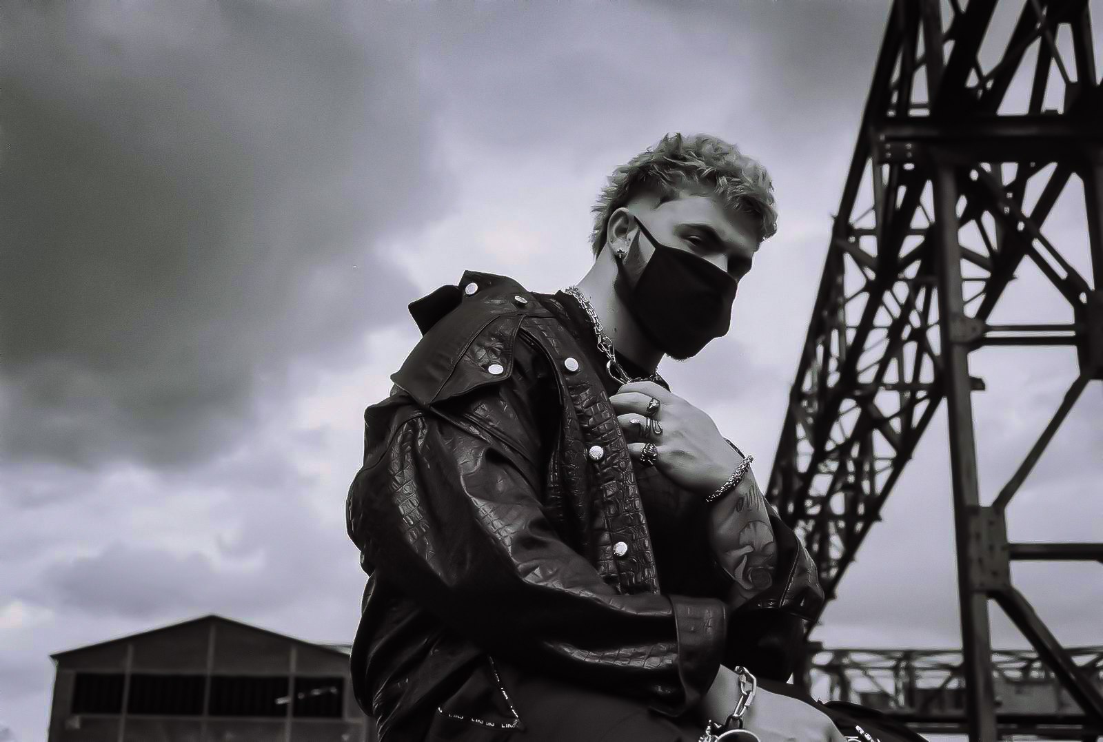 A black and white image of a man with a faded haircut, wearing a leather jacket and a mask. By NinoTurbaProductions